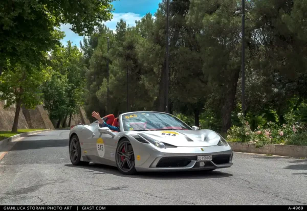 Il passeggero di una Ferrari grigia saluta il pubblico